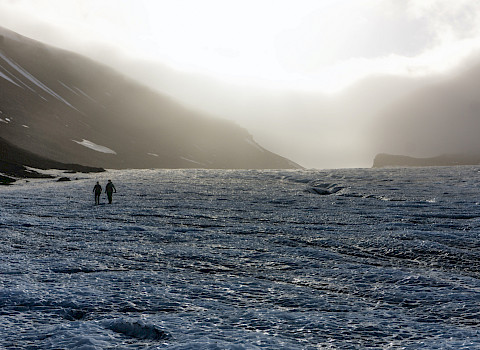 Two hikers are descending the glacier toward Longyearbyen.