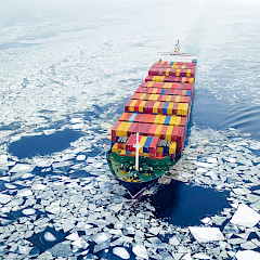 Aerial view of a container ship in icy waters.